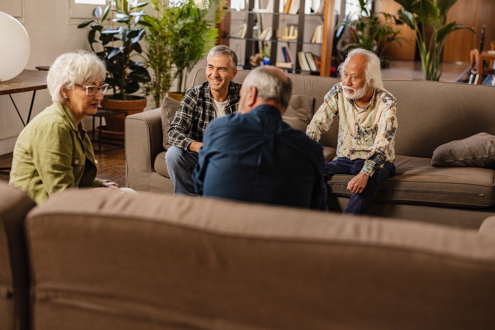 group of multiracial senior friends talk about their friendship in their living room