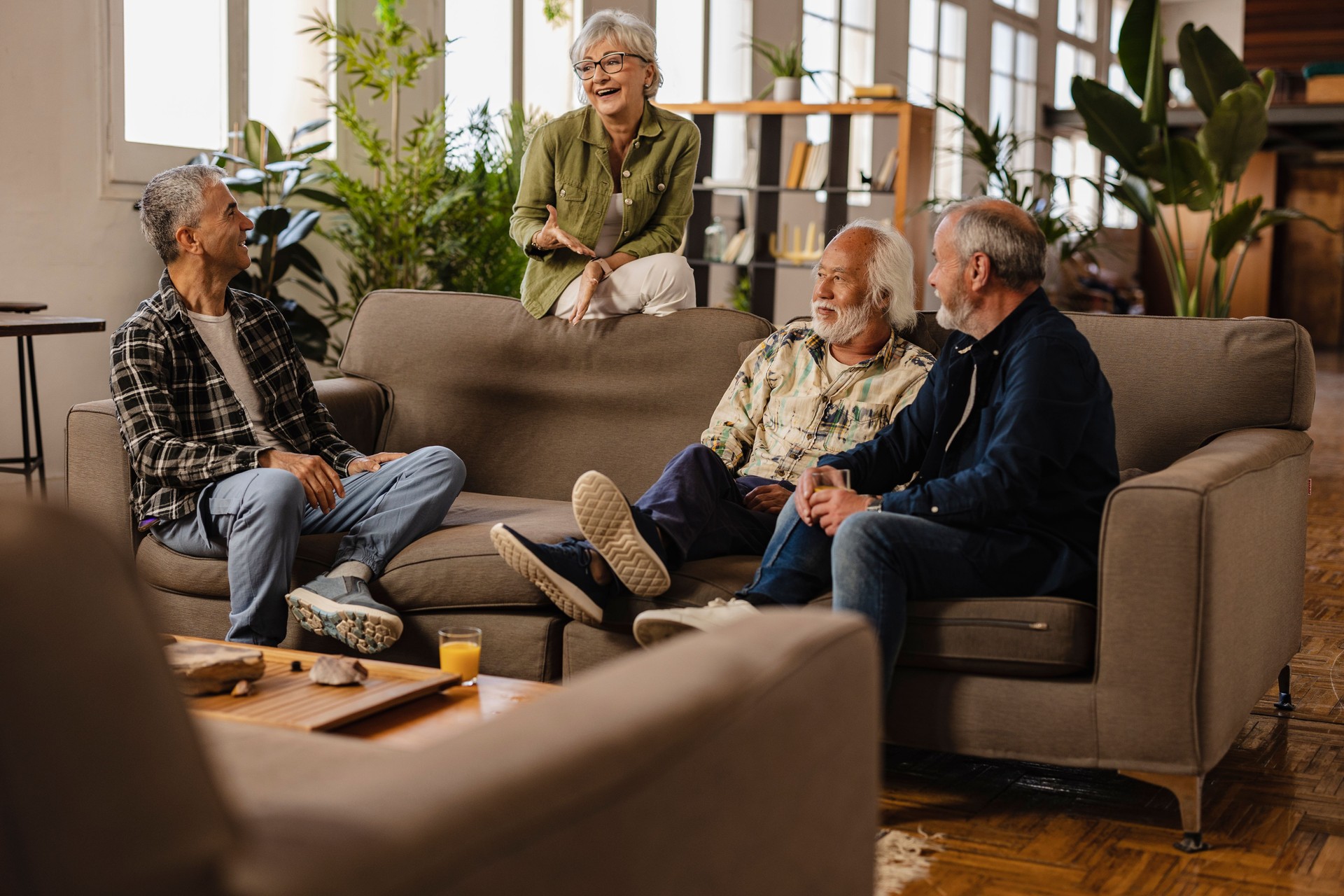 group of generational senior diverse friends meeting at home having fun - multiracial friends on sofa chatting -